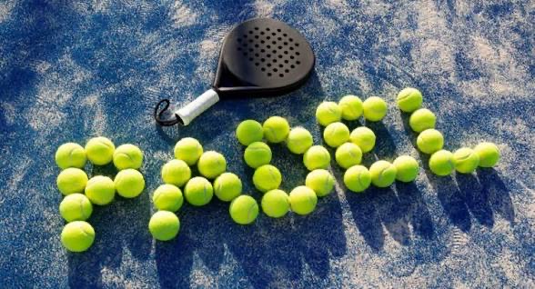 A padel racket beside yellow balls spelling out PADEL on a blue court.